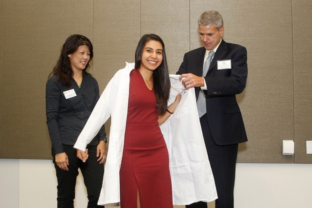 William Talbot helps Stephanie Kabeche into her new lab coat at Stanford.